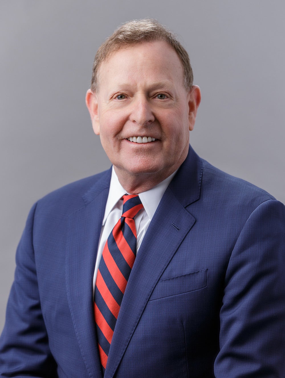 photo of Dr. Robert A. Barish in a blue jacket with a red and blu striped necktie, smiling