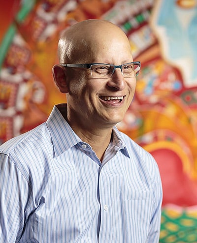 photo of Dr. Crespo wearing glasses and smiling in front of colorful mural