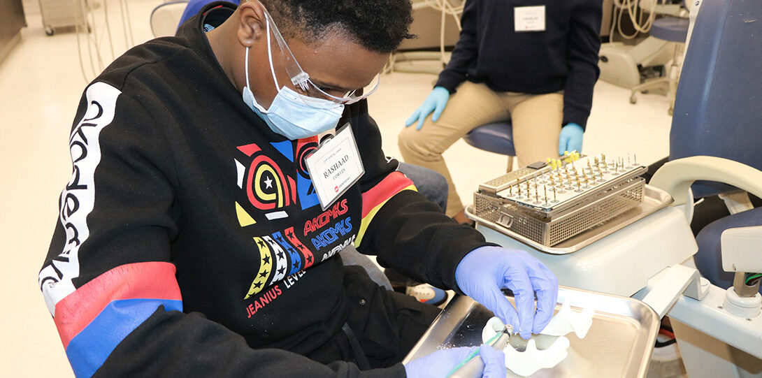 young Black man in a mask engaging in experiential learning about dentistry