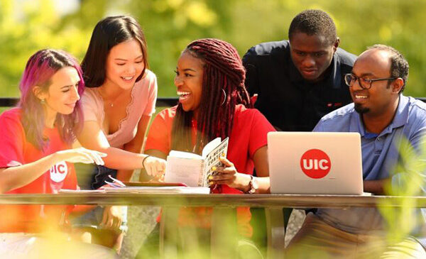 a diverse group of students working and laughing together on the UIC campus