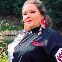 Chef Jessica standing in an open field and looking into the camera, wearing a chef's jacket with a tribal paw insignia on the sleeve