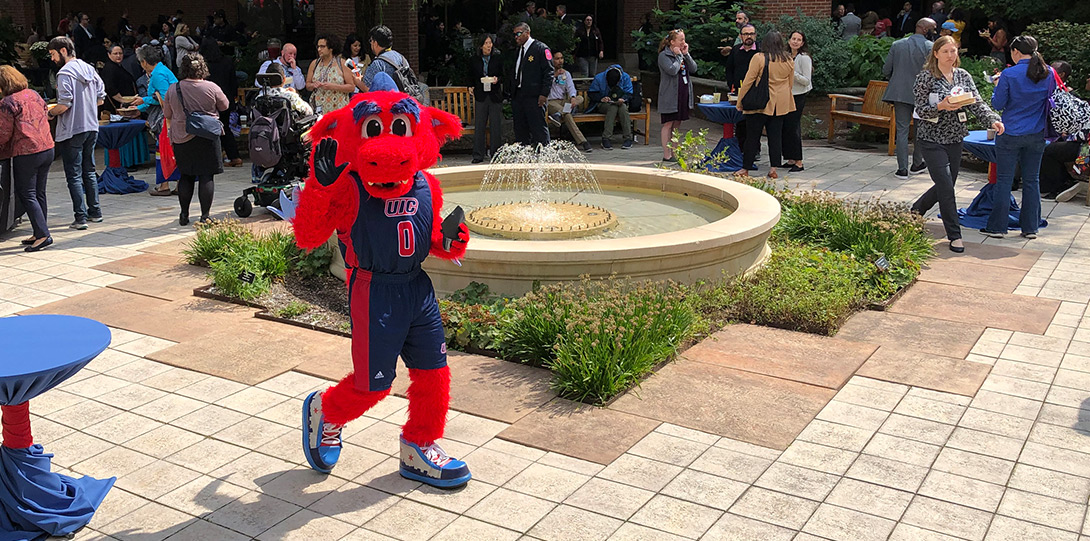 person wearing of fuzzy red dragon costume and dancing near the fountain