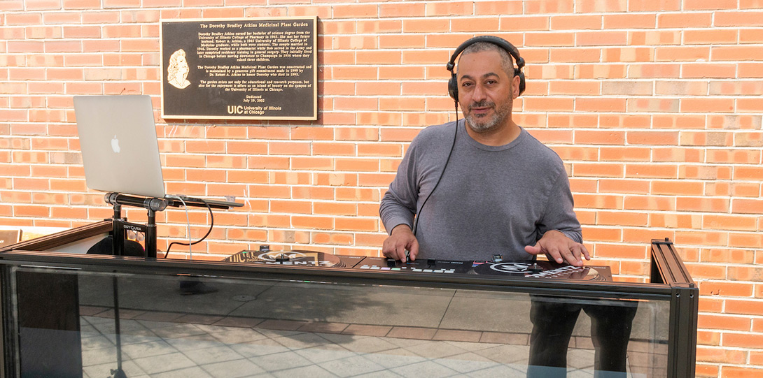 man wearing headphones and standing behind a DJ booth as he mixes music