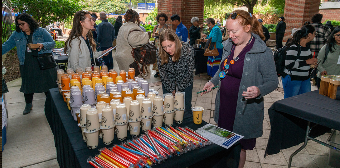 women at a table with a variety of cups of tea and multi-colored straws
