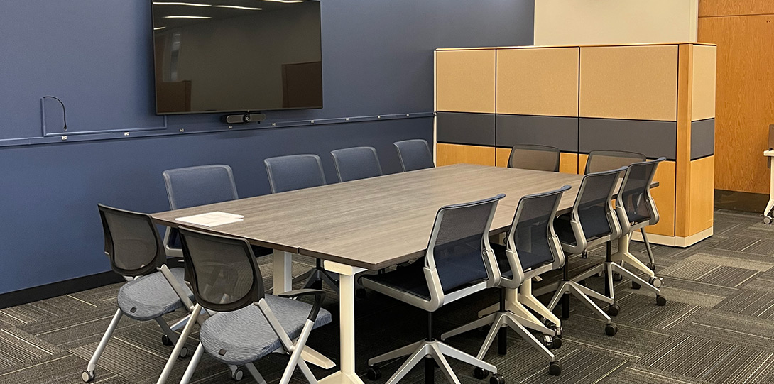 conference table with 10 chairs and a large screen monitor on the wall
