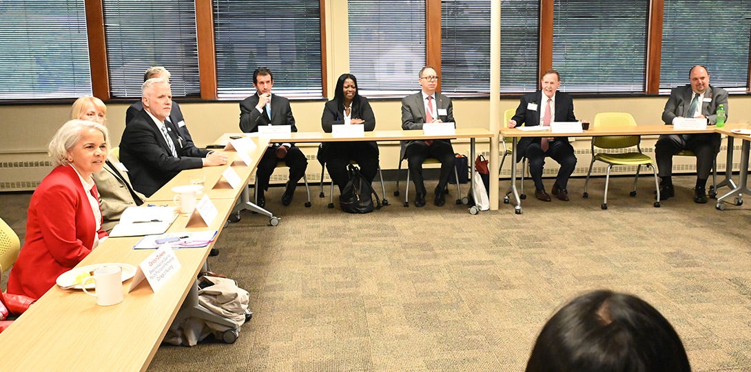 A conference room with the various participants seated at tables arranged in a large square.