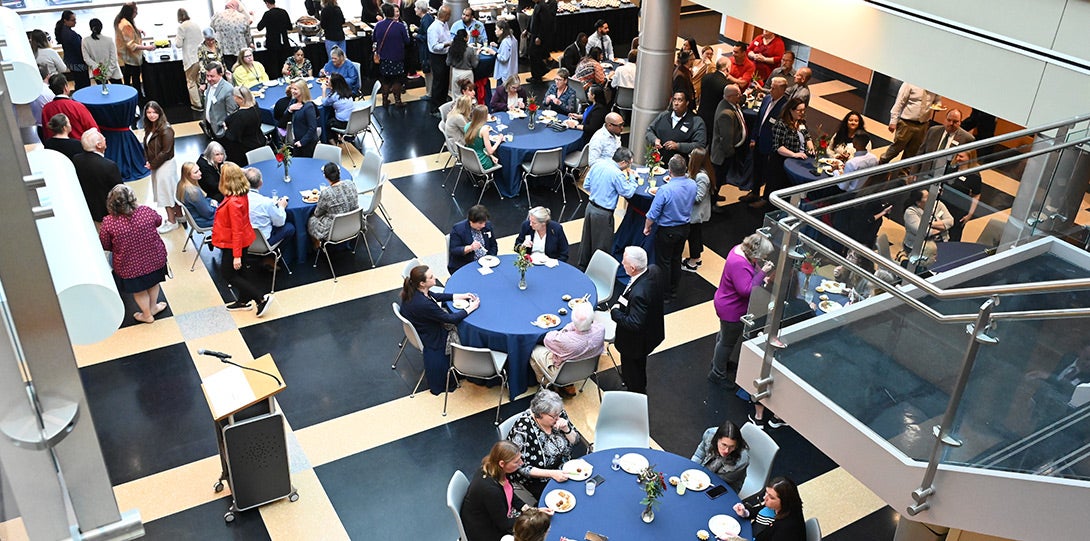 wide view looking down at an open pavilion filled with tables and people conversing and enjoying refreshments