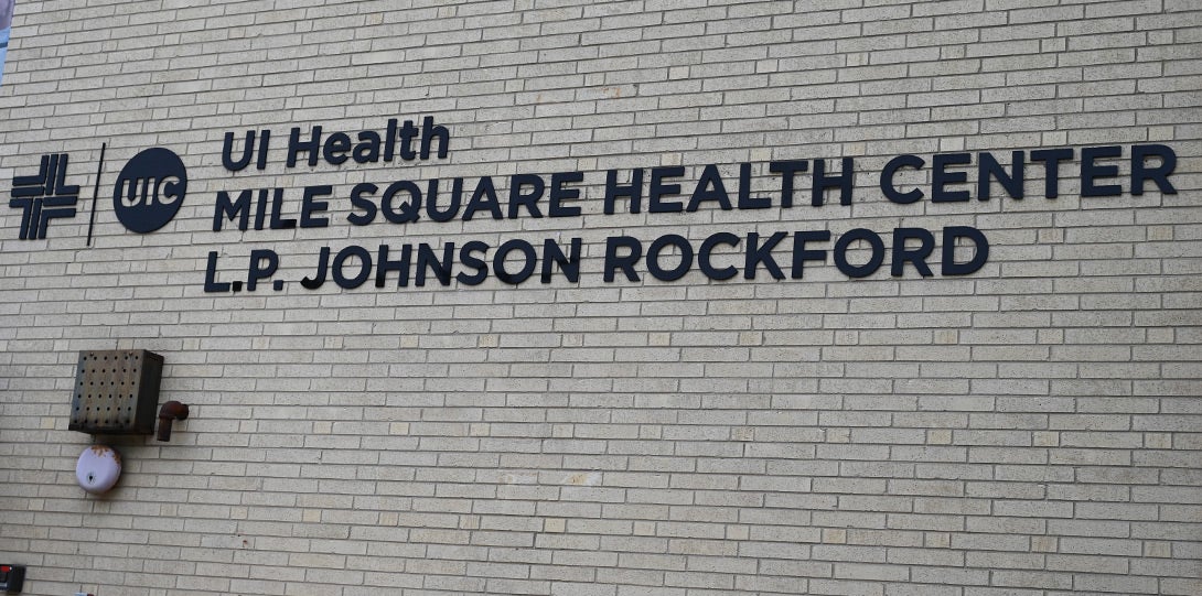 the sign of the health center showing a UI health logo and the text Mile Square Health Center L.P. Johnson Rockford all set on an exterior wall of light-colored bricksd