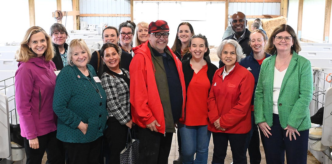 various tour attendees wearing jackets and posing together in a clean, well-lit, modern barn