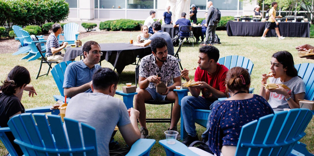 A diverse group of people sitting and conversing in a circular arrangement of lawn chairs