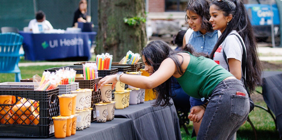 three young woman looking at a table adorned with cups of different flavors of tea