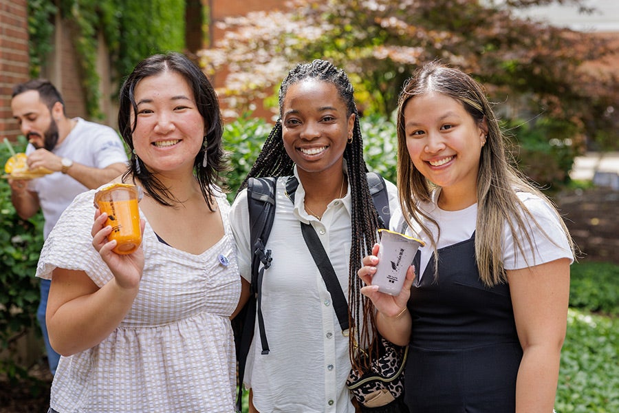 three young woman, one Asian, one African American and one Latinx, smiling and holding cups of cool boba tea