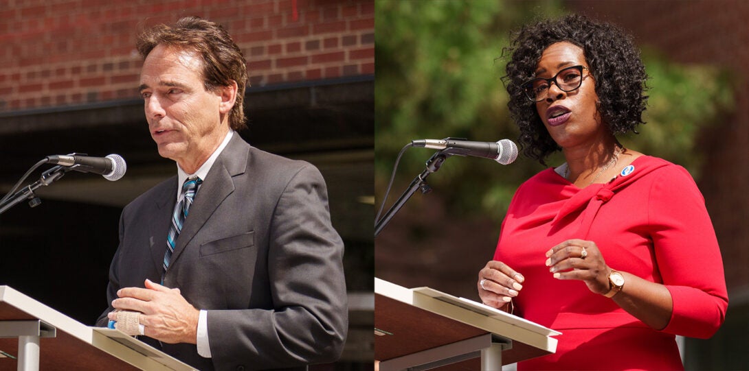 At left, a man in a gray suit standing at a podium and speaking into a microphone. At right, and African American woman in a red dress standing at a podium and speaking into a microphone.