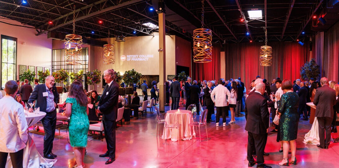 A colorful celebration venue, with many people mingling in groups and at tables.